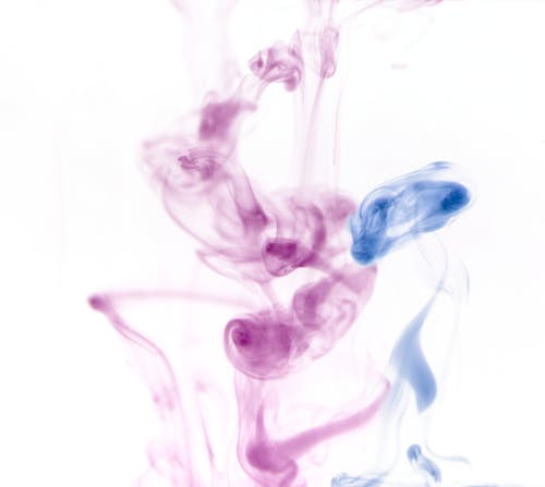 Closeup of blue and purple coloured light swirling transparent smoke on white background
