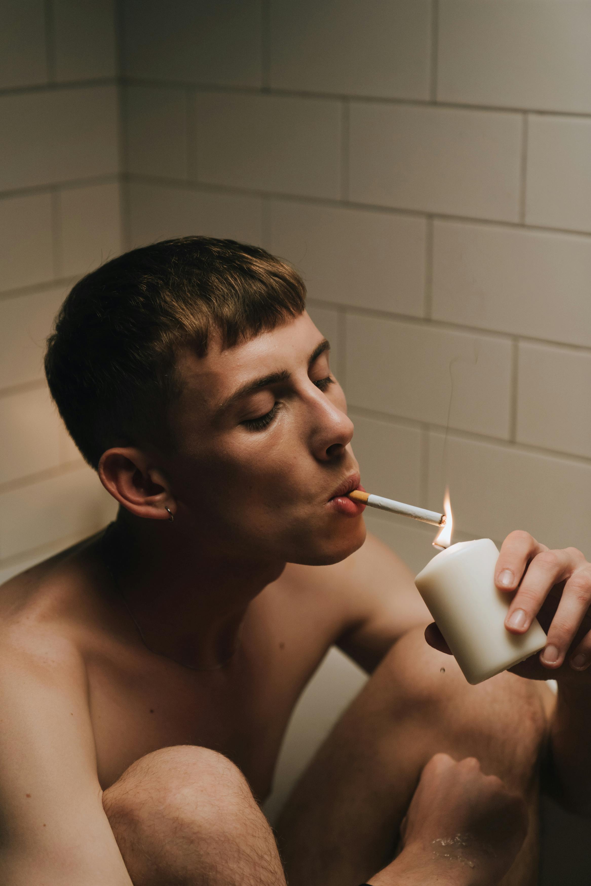 a man lighting a cigarette with a candle