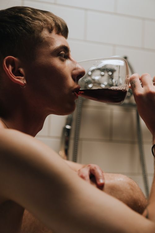 Free Side view of a man savoring red wine in a cozy, dimly lit environment. Stock Photo