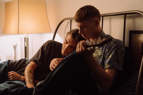 Free Man in Printed Shirt Playing Guitar Beside Man Leaning on Him Stock Photo