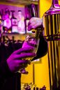 Unrecognizable male barkeeper pouring alcohol beer out of tap into glass while working in bar at pub counter on blurred background