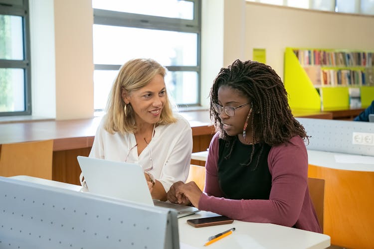 Young Ethnic Female Student Doing Assignment With Tutor In University