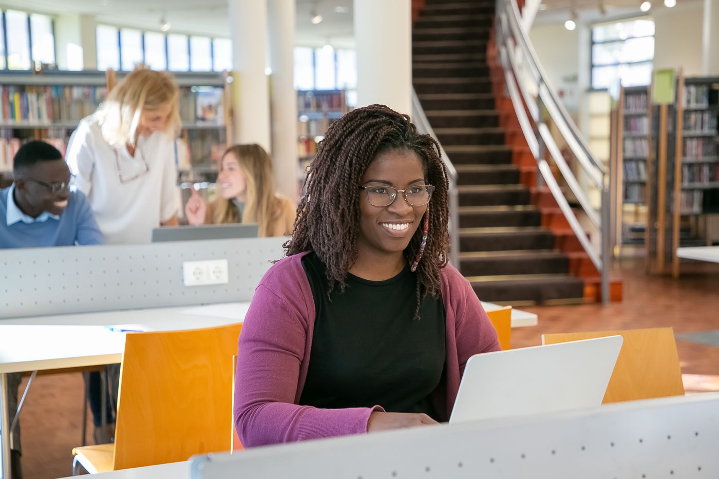Students working with laptops and books in a library