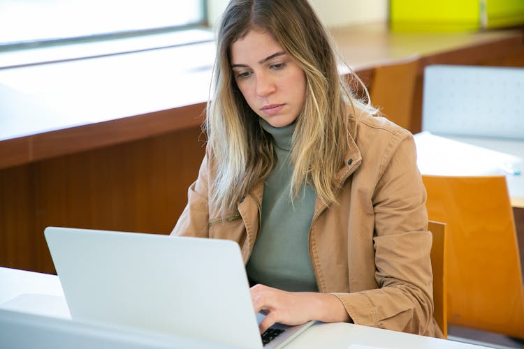 Serious Woman Working On Laptop In Library