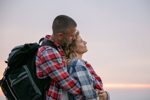 赤青と白の格子縞のドレスシャツの男黒のジャケットの女性にキス