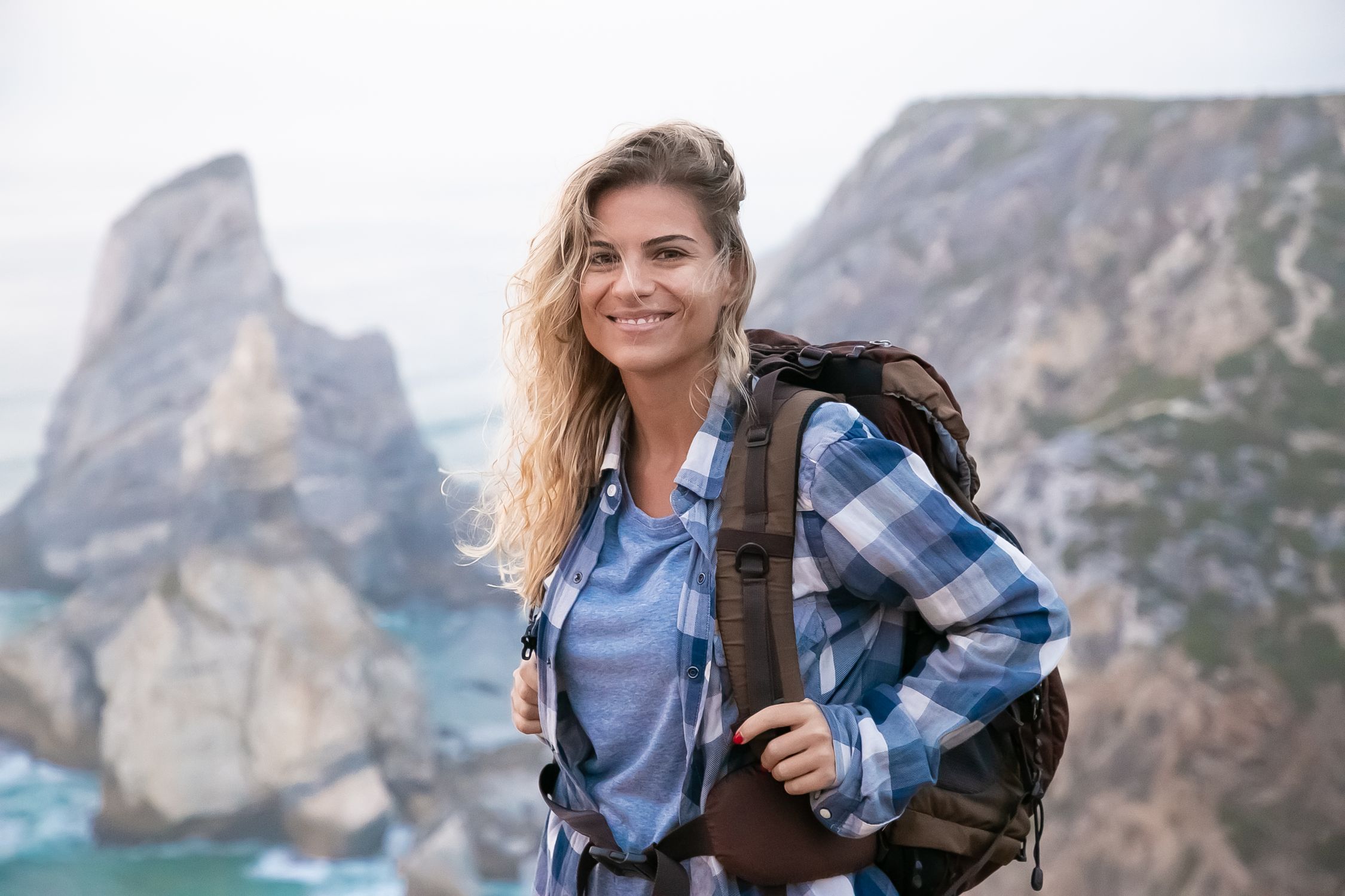 Woman with backpack hiking on coastal cliffs