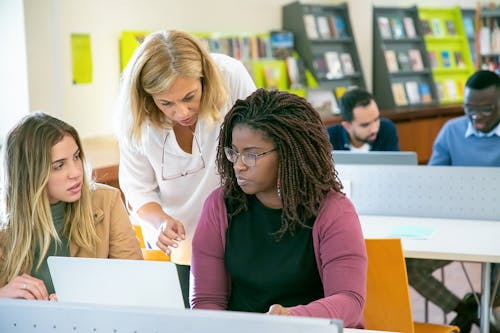 Gruppo Di Studenti Multirazziali Che Studiano In Biblioteca Con L'insegnante