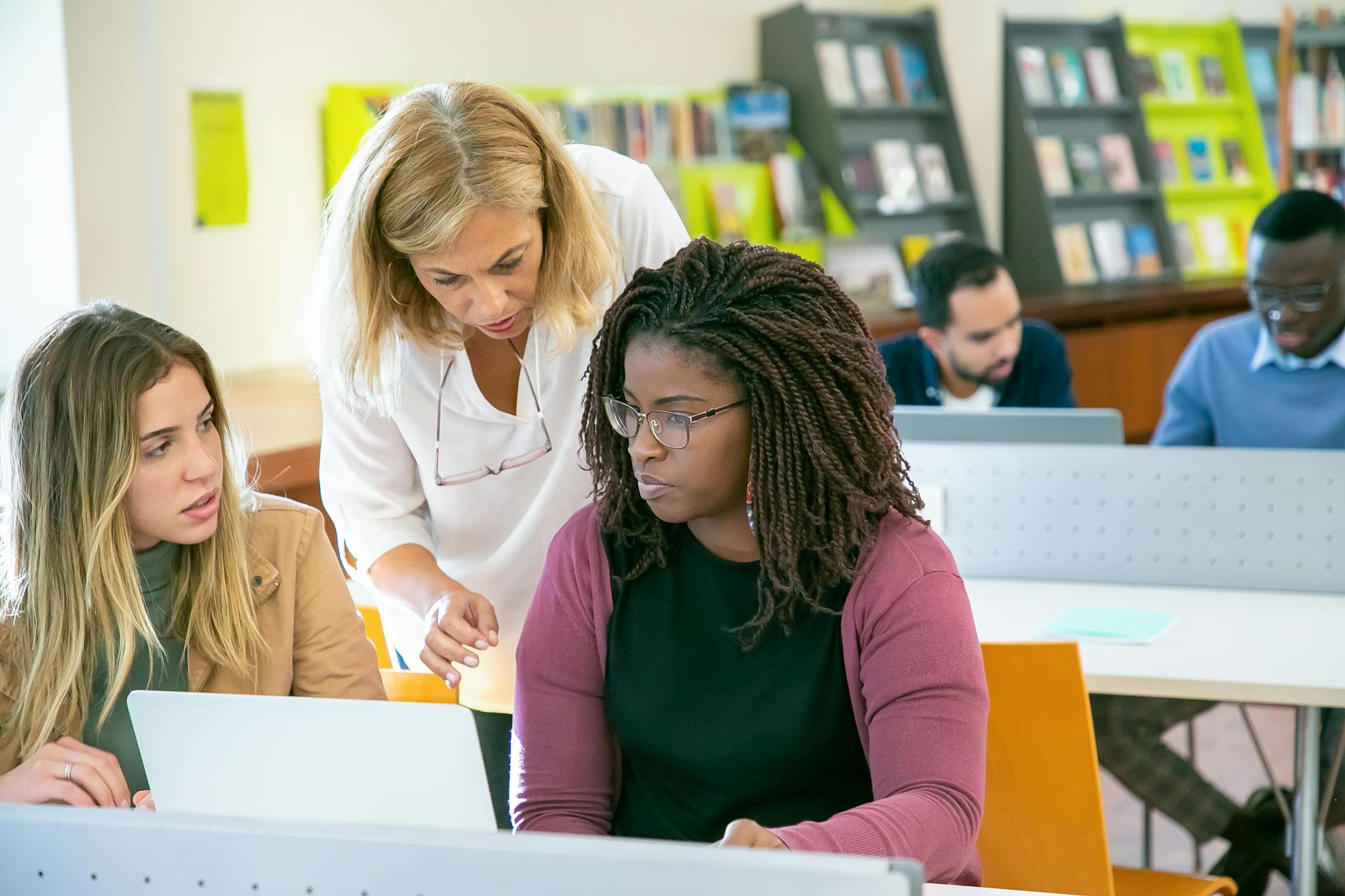 Group of multiracial students studying in library with teacher