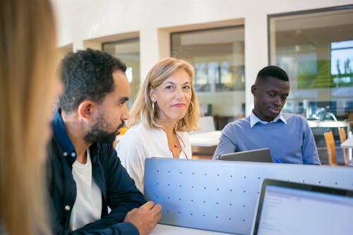 Group of diverse students doing research on laptops with teacher