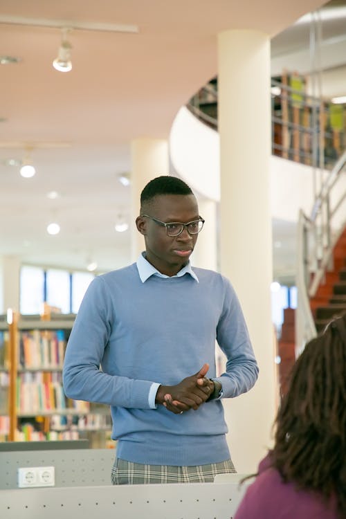 Black student standing in front of audience in library