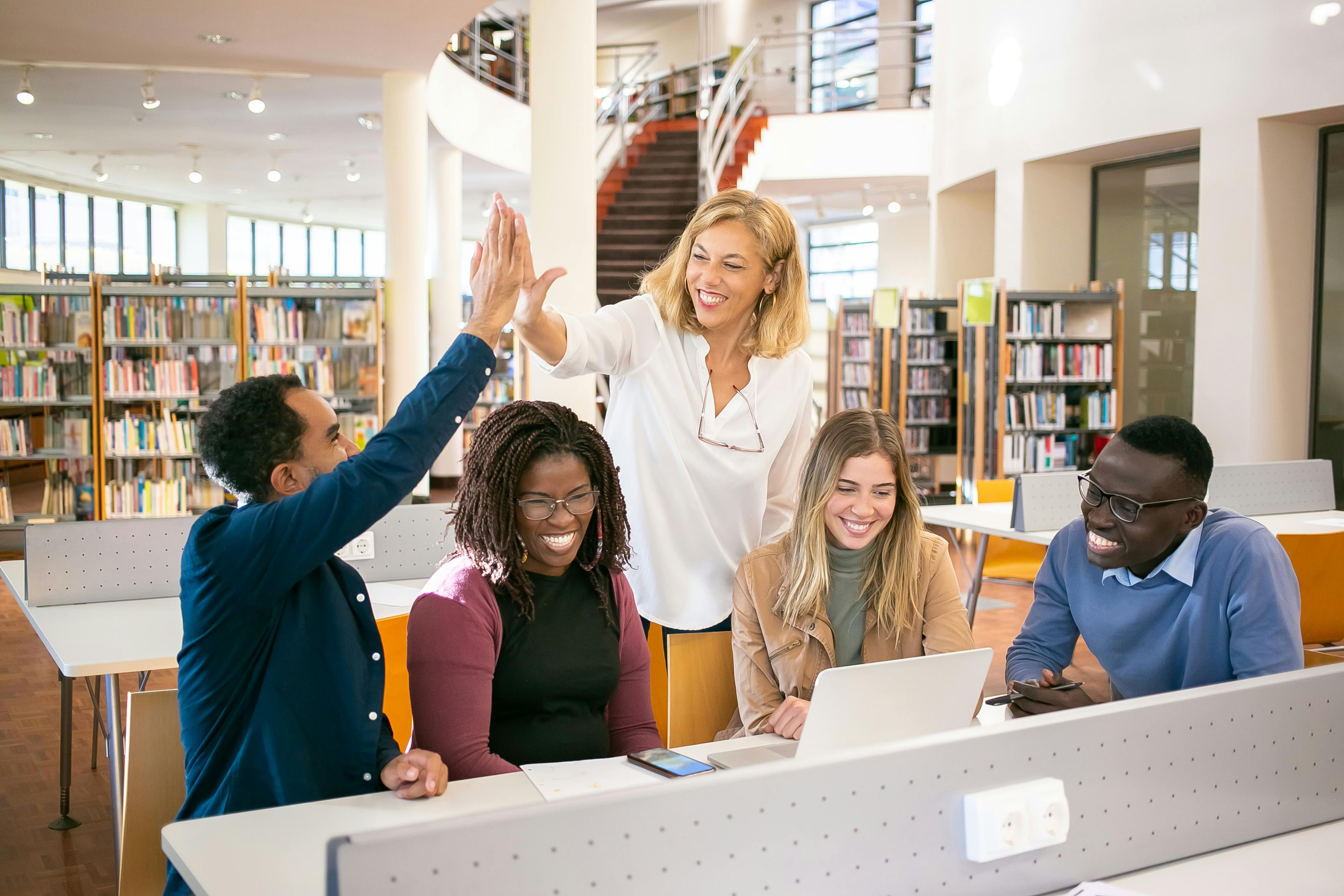 cheerful multiethnic students having high five with teacher