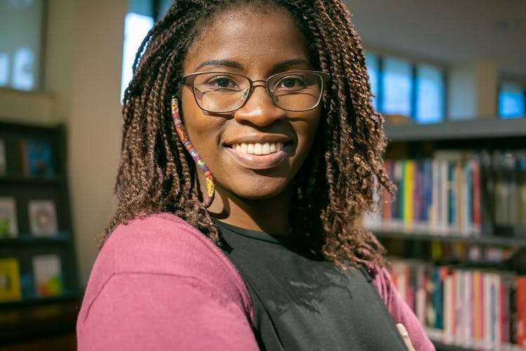 Cheerful Black Woman Standing In Bookstore