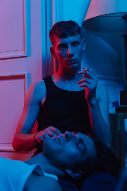 Free Two young adults in artistic lighting, one smoking a cigarette, creating a dramatic and moody scene. Stock Photo
