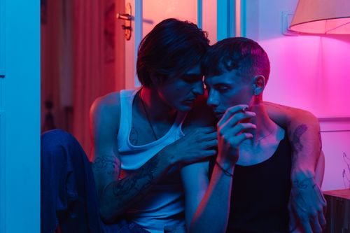 Free Close-up shot of a loving LGBT couple embracing under moody neon lighting indoors. Stock Photo