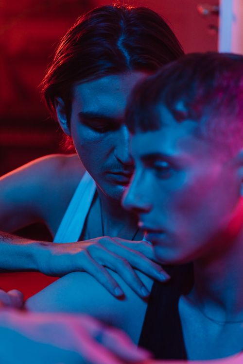 Free Close-up portrait of a couple sharing an emotional moment under vibrant neon lights. Stock Photo