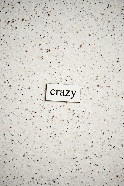 Free Word 'crazy' on a minimalist speckled background, ideal for design projects. Stock Photo