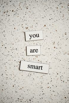 Creative arrangement of motivational words 'You are Smart' on a speckled background.