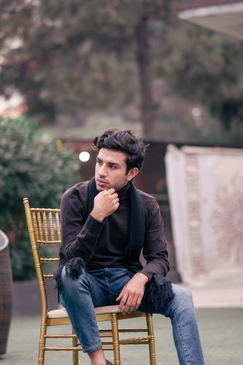 Free Stylish young man in casual attire sitting outdoors in Sialkot, Pakistan. Stock Photo