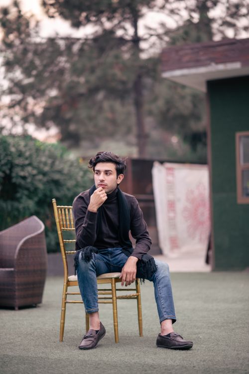 Free Man in casual outfit sitting on a chair outdoors, contemplating. Stock Photo