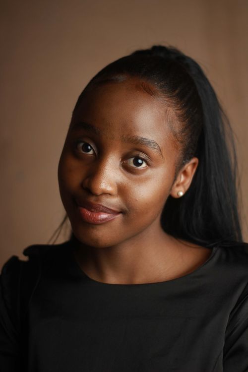 Free A close-up portrait of a young woman with a warm smile, wearing black. Stock Photo