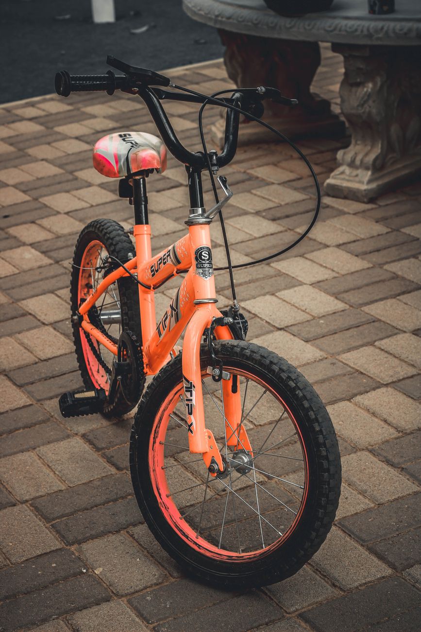 れんが敷きの庭先に置かれたオレンジ色の子ども用自転車