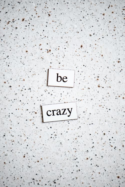 Free "Be crazy" text on a speckled background, conveying positivity. Stock Photo