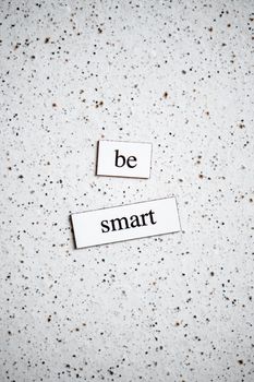 Minimalist photo of 'be smart' phrase on a speckled surface, perfect for motivation.
