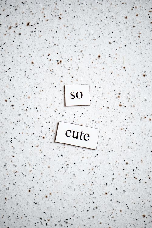 Free Magnetic words 'so cute' placed on speckled white paper. Simple and modern design. Stock Photo