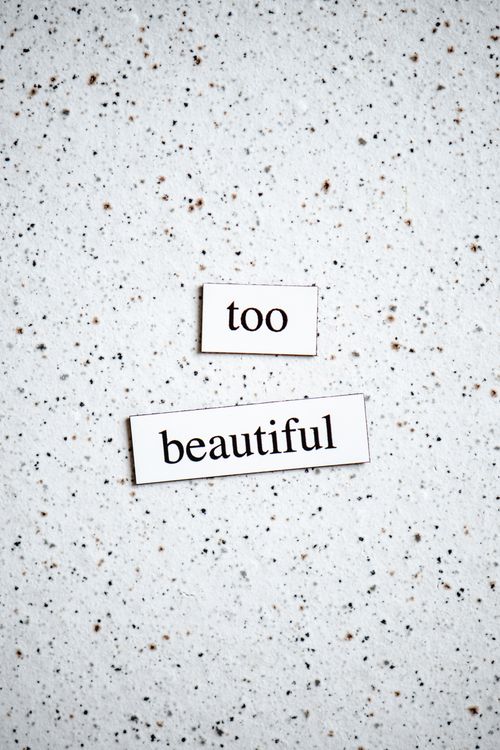 Free A minimalist art piece with the phrase 'too beautiful' in black and white on a speckled surface. Stock Photo