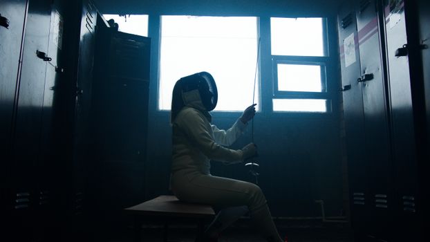 A Fencer Sitting on a Bench in a Locker Room