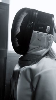 Close-up of a fencer in traditional gear, captured in black and white.