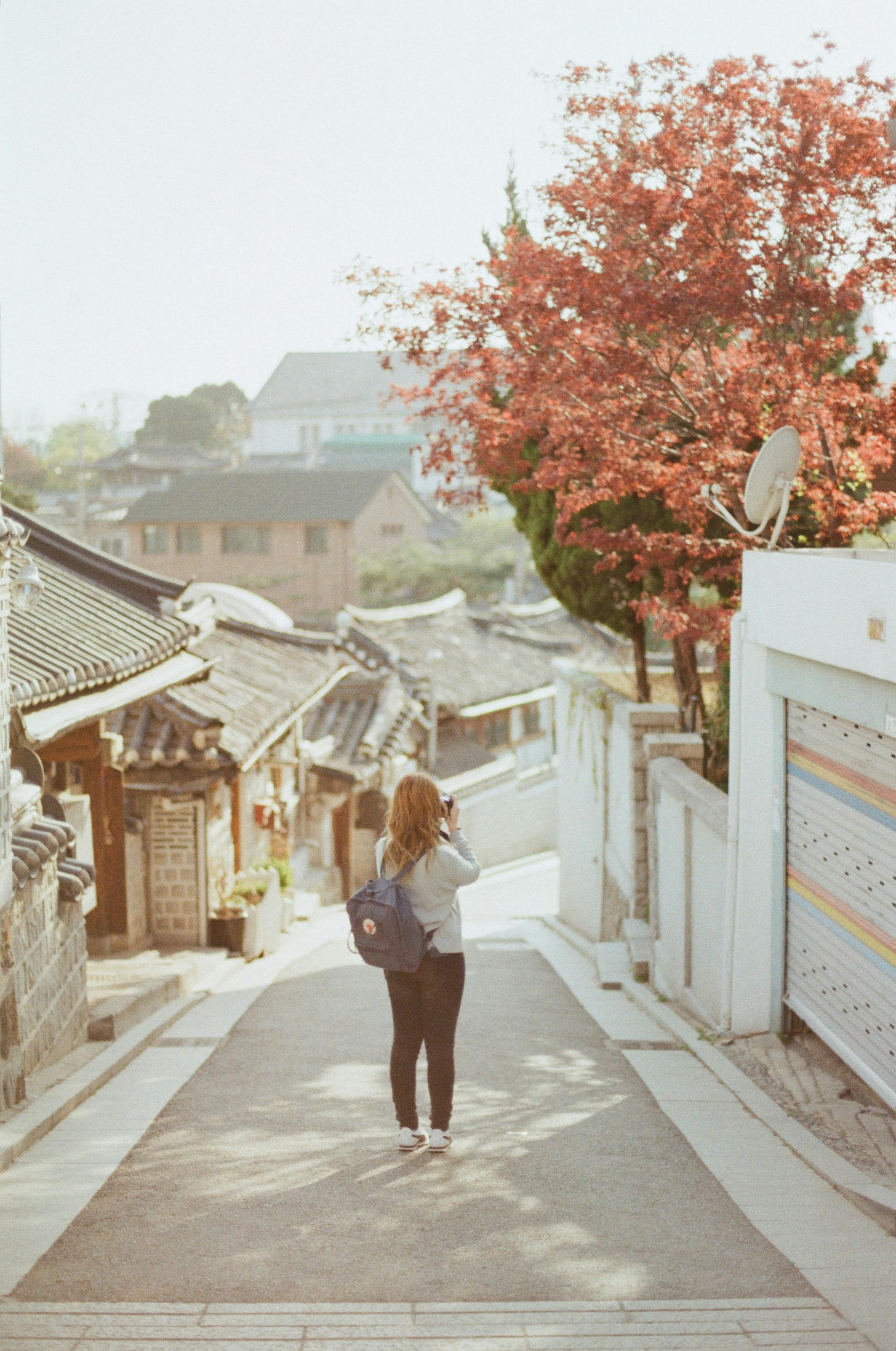 一位女士在樱花盛开、建筑古朴的街道上拍照