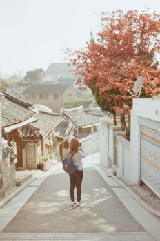 一位女士在樱花盛开、建筑古朴的街道上拍照