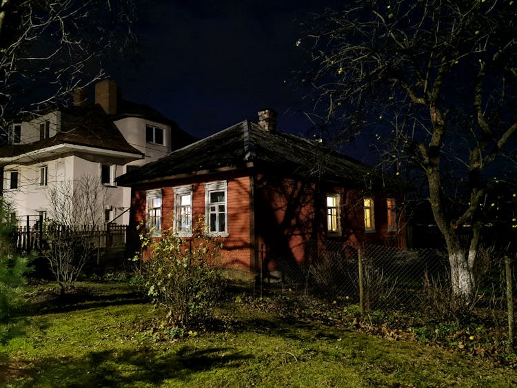 Old Wooden House With Light Inside At Night