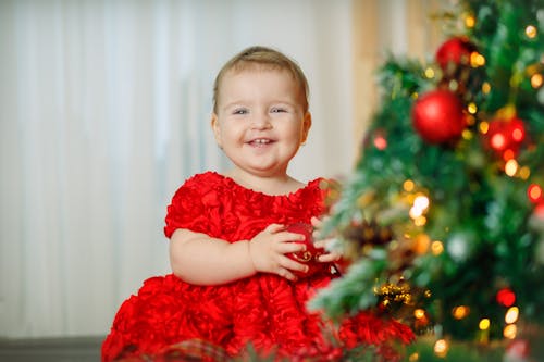 Young Girl in Red Dress Holding a Christmas Ball