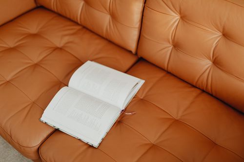 Free An open book lies on a stylish brown leather sofa, symbolizing leisure and relaxation. Stock Photo