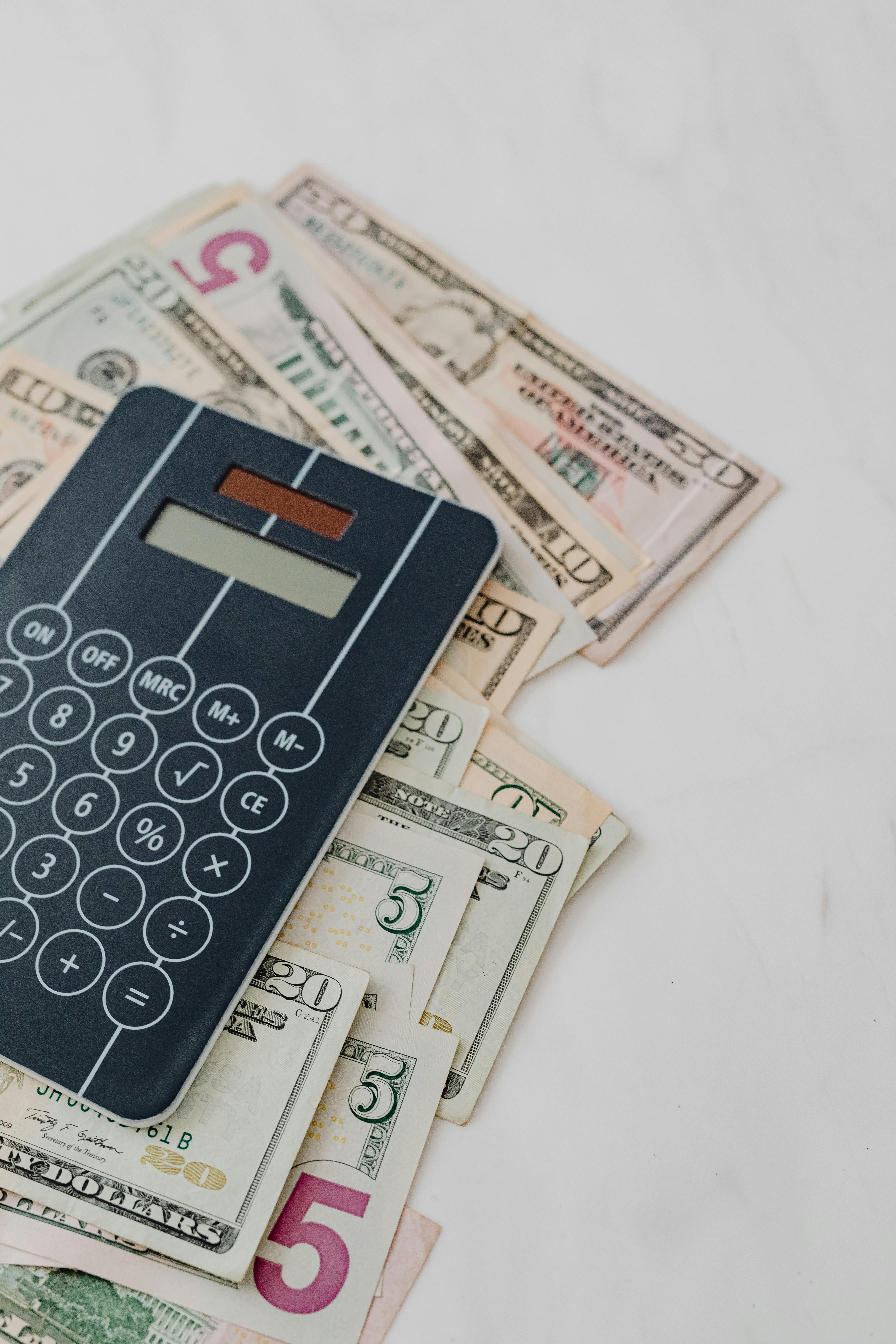 black and white calculator on top of dollar bills