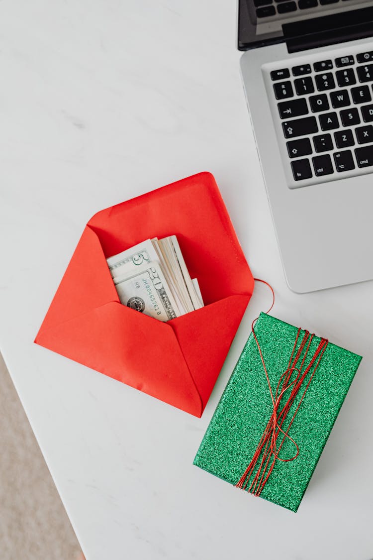 Money In Envelope And Present On Table