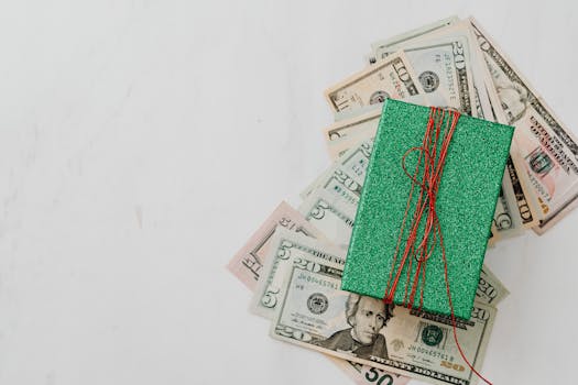 Green gift box on a pile of dollar banknotes showcasing a concept of monetary value and gift-giving.