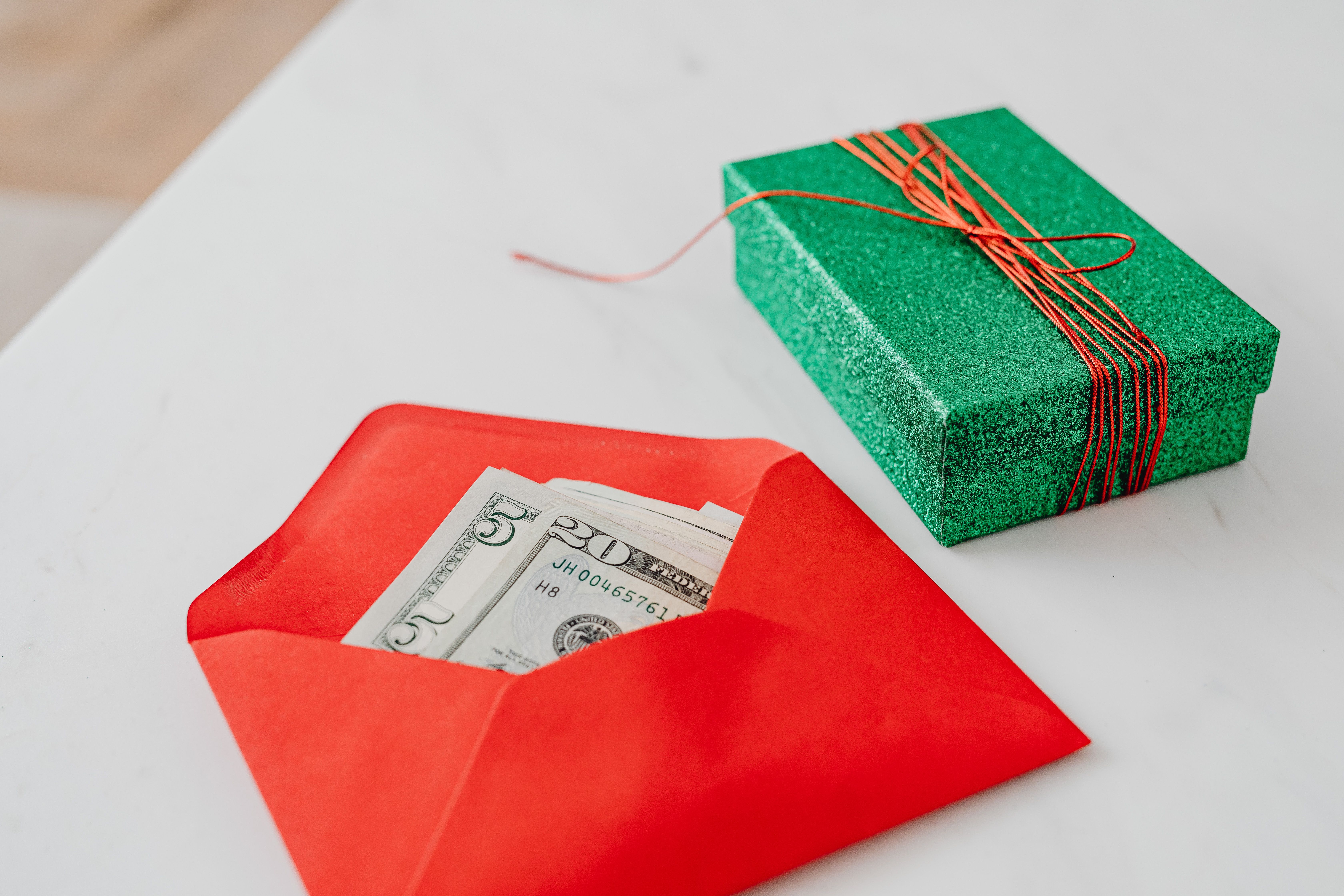 A festive red envelope with US dollar bills next to a gift-wrapped green box, perfect for special occasions.