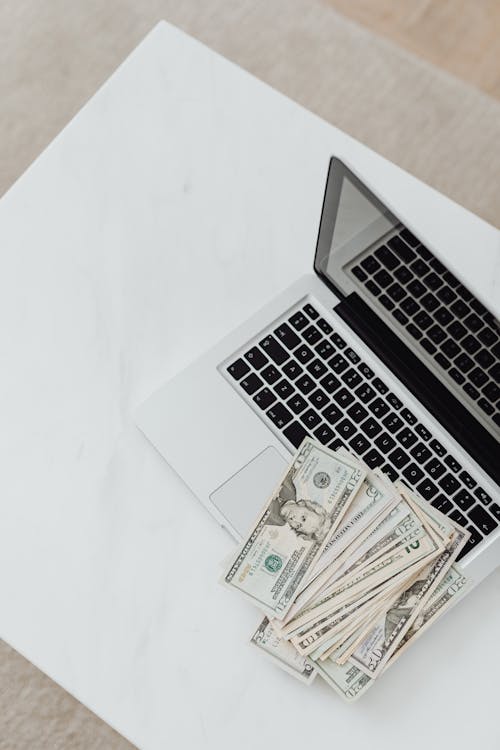 Free Overhead Shot of Dollar Bills on Top of a Laptop Stock Photo