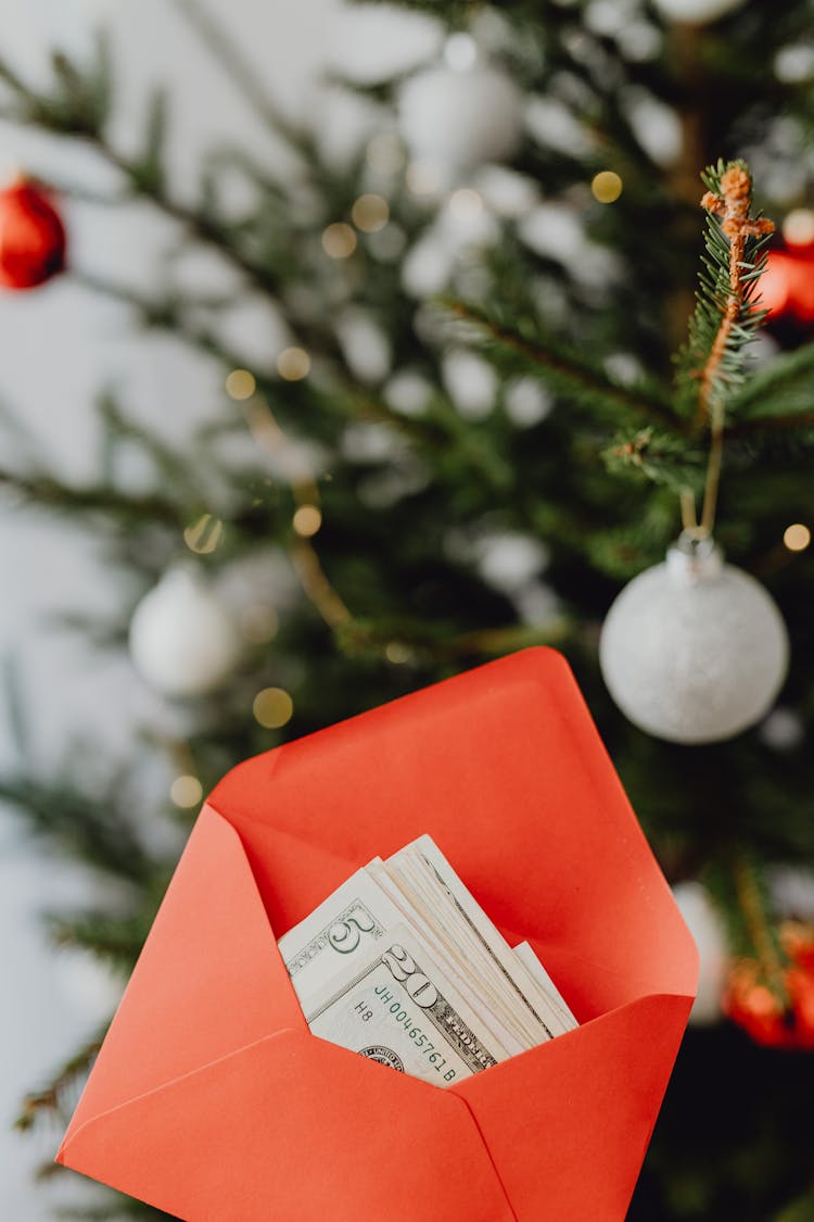 Money In Envelope In Front Of Christmas Tree