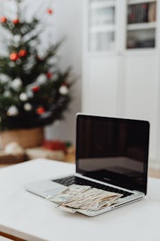 Laptop with cash in a home office decorated for the holidays.