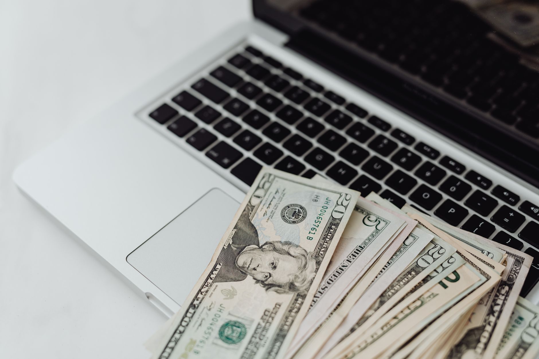Close-up of US dollar banknotes on a laptop keyboard symbolizing online finance and technology.