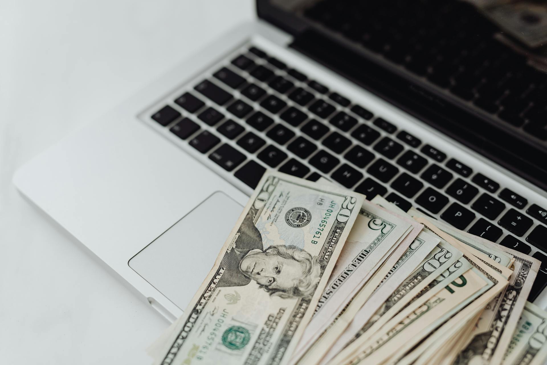 Close-up of US dollar banknotes on a laptop keyboard symbolizing online finance and technology.