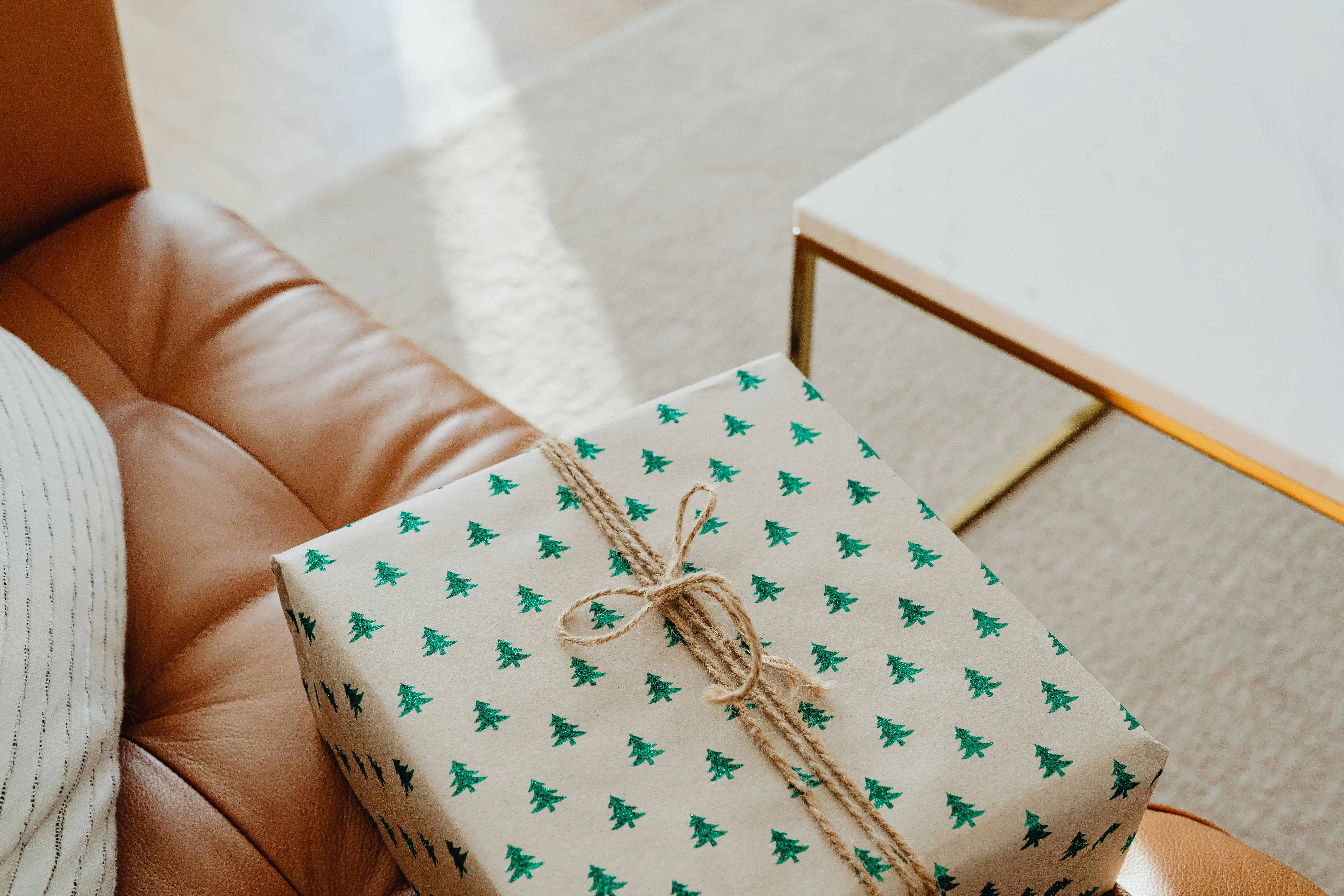 A wrapped Christmas gift on a brown leather couch in a modern living room, exuding warmth and festivity.