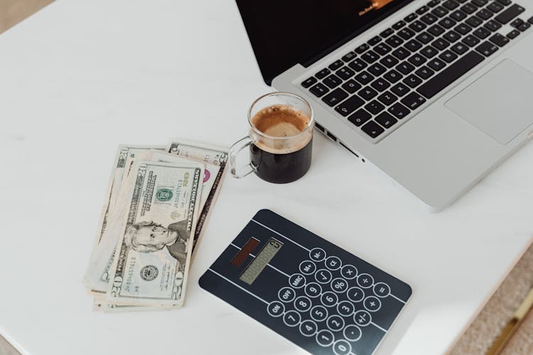 Money, Coffee, Calculator And Laptop On A Desk 