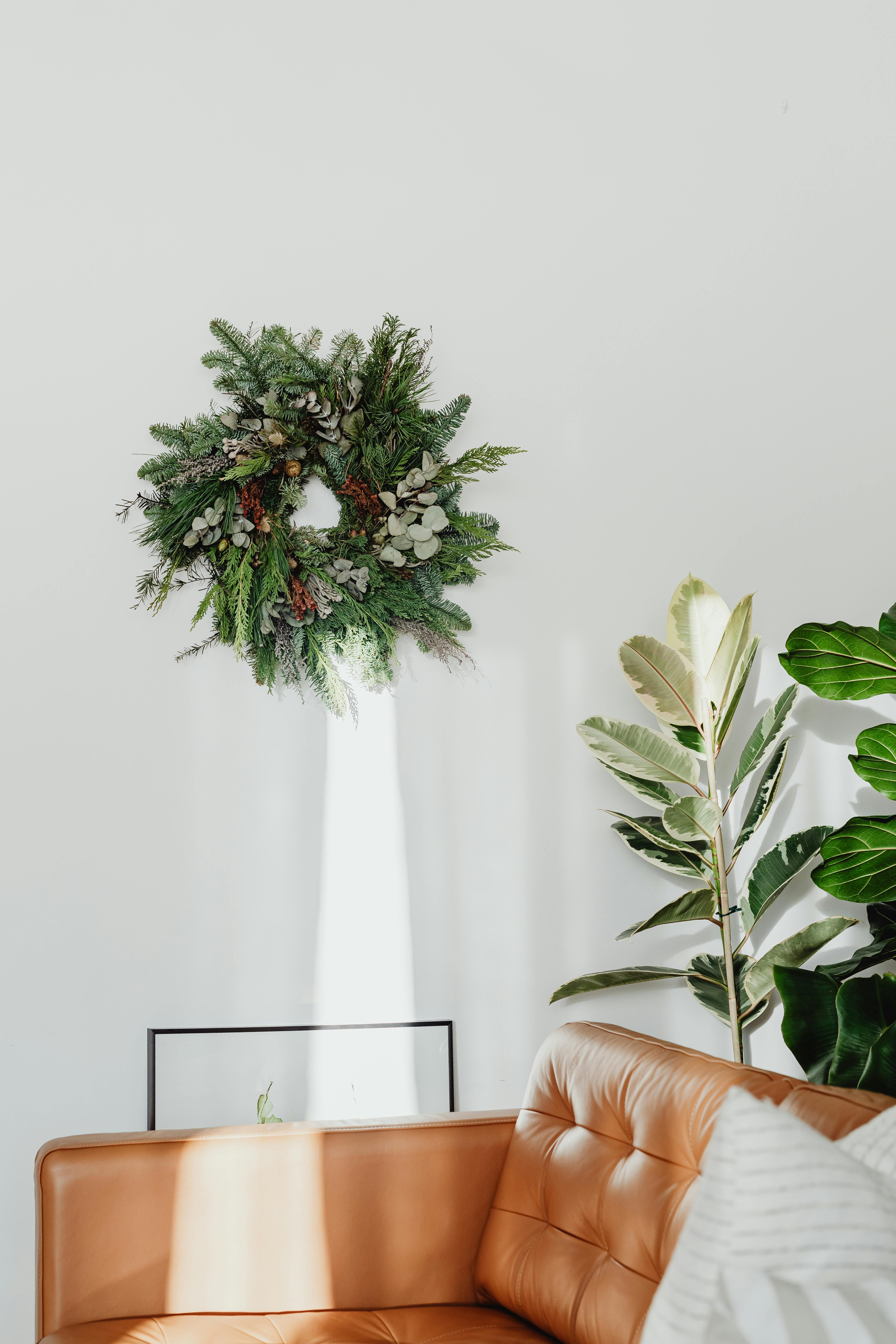 Bright living room with a wreath and houseplants, highlighting a cozy, minimalist style.