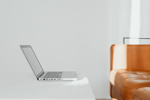 Free Orange Sofa, White Wall and Laptop Stock Photo