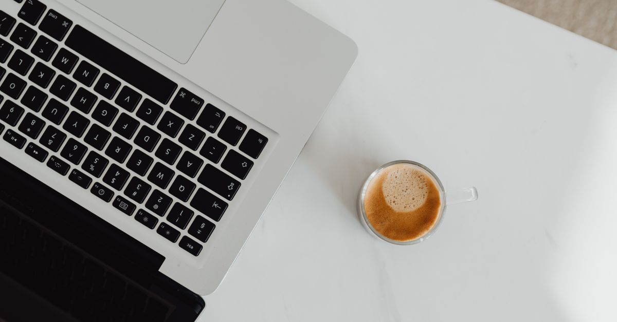 minimalist desk setup with a laptop, coffee cup, and a small shield icon symbolizing digital protection